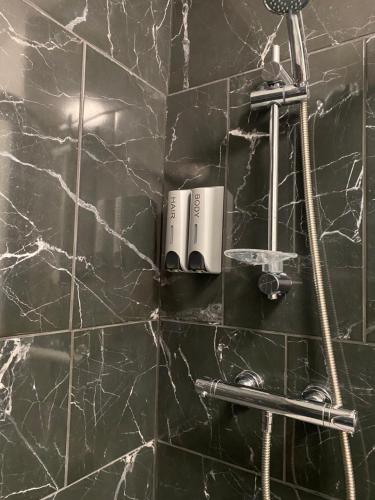 a bathroom with a black marble wall with a shower at The New Talbot Hotel in Southport