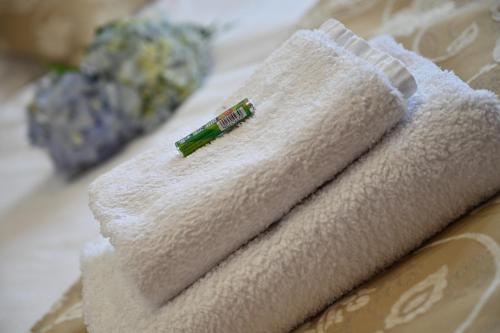 a pile of towels on a bed with a green needle at Apartmani Lucija in Ludbreg