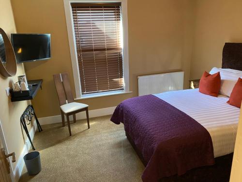 a bedroom with a bed and a window and a chair at The New Talbot Hotel in Southport
