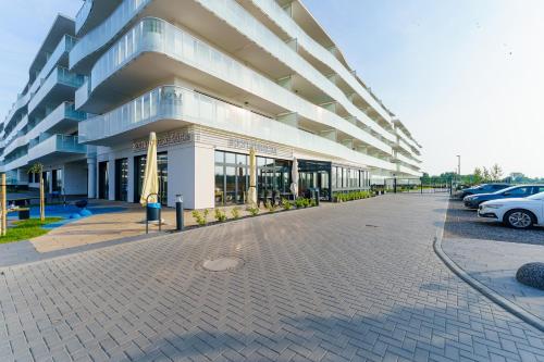 a large building with cars parked in a parking lot at FARO Apartamenty Polanki Aqua SPA Deluxe 4 baseny w cenie, Pools inklusive in Kołobrzeg