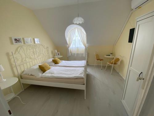 ein Schlafzimmer mit einem weißen Bett und einem Bogenfenster in der Unterkunft Vázsonyi vendégház in Balatonfüred