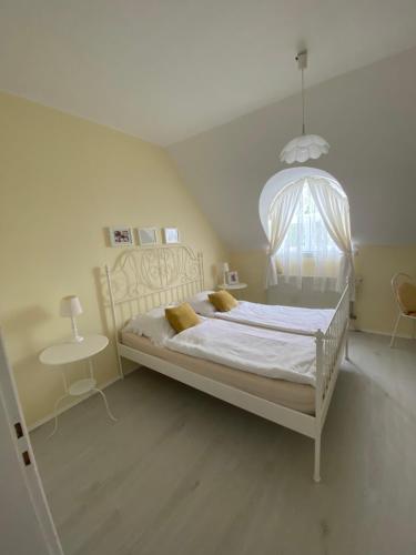 Schlafzimmer mit einem weißen Bett und einem Kronleuchter in der Unterkunft Vázsonyi vendégház in Balatonfüred