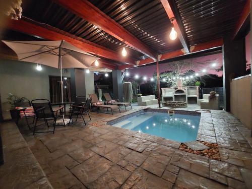a swimming pool with a table and chairs and an umbrella at Villa Pesca Self Catering accommodation in Richards Bay