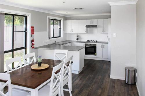 a kitchen with white cabinets and a wooden table and chairs at Quintet 1 157 in Tamworth