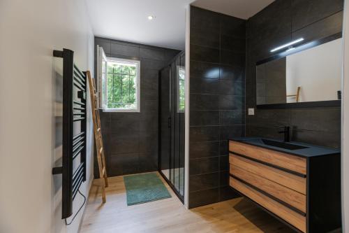 La salle de bains est pourvue de murs en carrelage noir et d'un lavabo. dans l'établissement Villa Graveyron - Maison avec piscine privée, à Berrias Et Casteljau