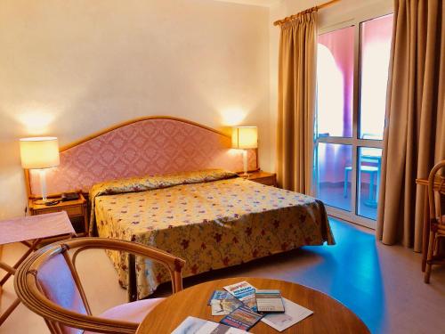 una camera d'albergo con letto, tavolo e finestra di Arthotel Gabbiano Azzurro Due a Marciana Marina