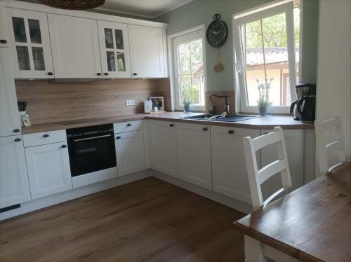 a kitchen with white cabinets and a wooden floor at Landidyll 
