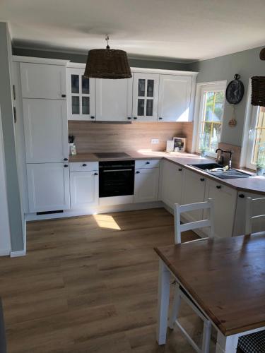 a kitchen with white cabinets and a wooden floor at Landidyll in Silenz