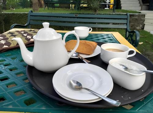 a table with a tea pot and cups and saucers at Aestus Adventure and Wellness Centre in Kasauli