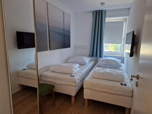 ヴァンガーラントにあるTief 10 Wohnung 102 Heimathafenのベッド2台と鏡のある小さな部屋
