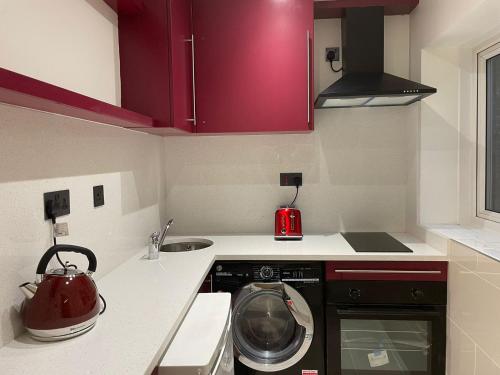 a kitchen with red cabinets and a washing machine at King Studio Apartment with Garden and Parking in Ealing