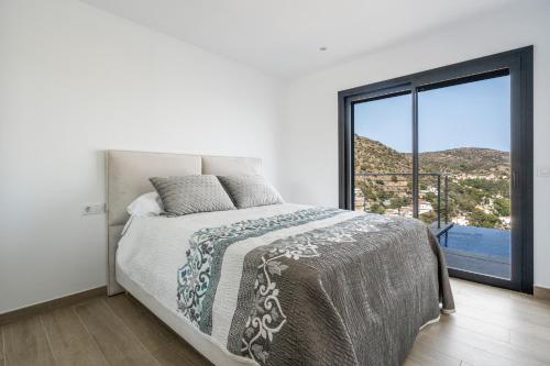 ein Schlafzimmer mit einem Bett und einem großen Fenster in der Unterkunft Villa Welcs EMP 083 con piscina infinita in Roses