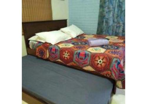 - un lit avec une couette colorée dans l'établissement Homestay Pagar Buruk Bukit Merah L6- FAN ONLY, à Simpang Ampat Semanggol
