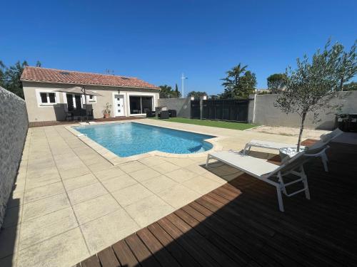 einen Hinterhof mit einem Pool, einem Stuhl und einem Haus in der Unterkunft Jolie maison avec piscine in Rochefort-du-Gard