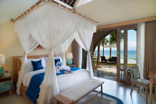 a bedroom with a canopy bed with a view of the ocean at The Sankara Beach Resort - Nusa Penida in Nusa Penida