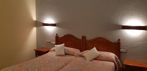 1 dormitorio con 1 cama con 2 lámparas en la pared en San Glorio, en Llánaves de la Reina
