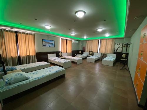 een kamer met 4 bedden en groene verlichting bij Mang’o Hostel in Aqtau