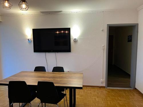 une table à manger avec des chaises et une télévision murale à écran plat dans l'établissement Feel at home - central & cosy, à Bâle