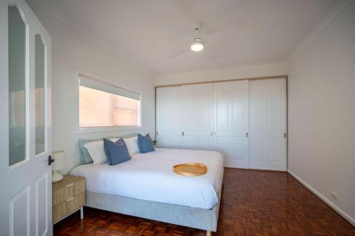 a bedroom with a white bed with a wooden bowl on it at Daydream - 150m from the beach in Shellharbour