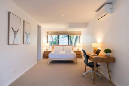 a bedroom with a bed and a desk with a computer at Absolute waterfront beach house in Minnamurra