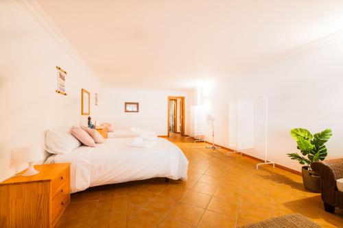a white bedroom with a bed and a table at Villa Arrifes in Albufeira
