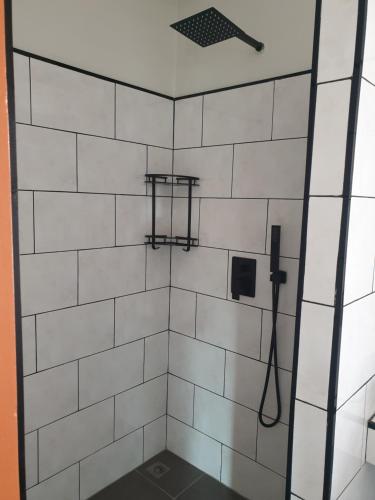 een witte betegelde douche met een zwart-witte tegelwand bij My Friend's House Villa in Ka Rorn