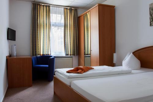 ein Hotelzimmer mit einem Bett und einem Stuhl in der Unterkunft Hotel Eckstein in Berlin
