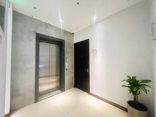 un corridoio con una porta e una pianta in vaso di oxy suites 2-06 at Shop House Meisterstadt Pollux Habibie a Batam Center