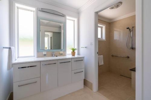 La salle de bains blanche est pourvue d'un lavabo et d'un miroir. dans l'établissement Bella Dawn, à Kiama