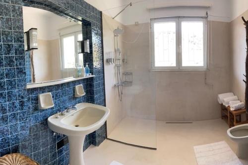 a blue tiled bathroom with a sink and a shower at Bellavista at Heraion Lagoon in Loutraki