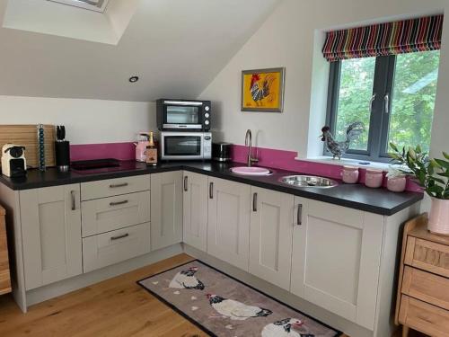 a kitchen with white cabinets and a black counter top at The Hen House A beautifully situated open plan chalet in Lothersdale