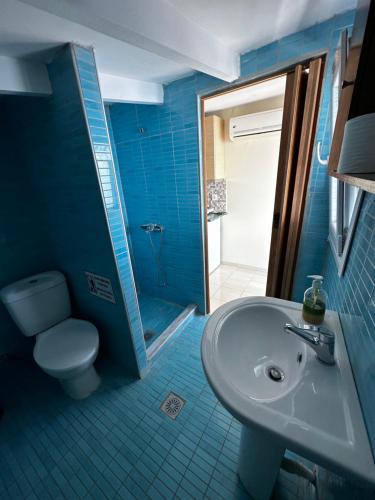 a blue bathroom with a toilet and a sink at Rooms Elena in Nea Potidaea