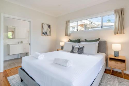 a white bedroom with a large white bed and a window at The Farmer s Retreat in Kiama