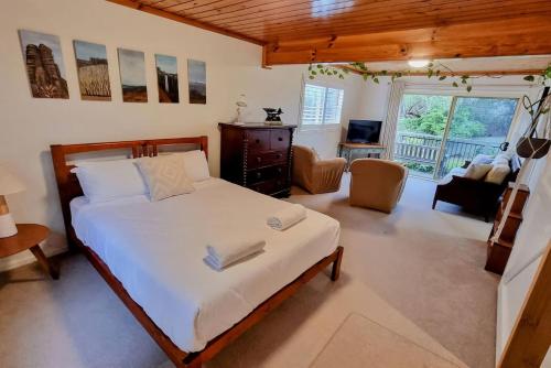 a bedroom with a bed and a living room at Blue Skies Beach House in Gerringong