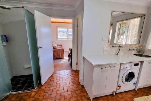 a bathroom with a sink and a washing machine at Blue Skies Beach House in Gerringong