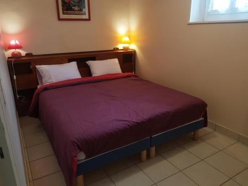 um quarto com uma cama com um edredão roxo em Gîte de Champdoré em Nanthiat