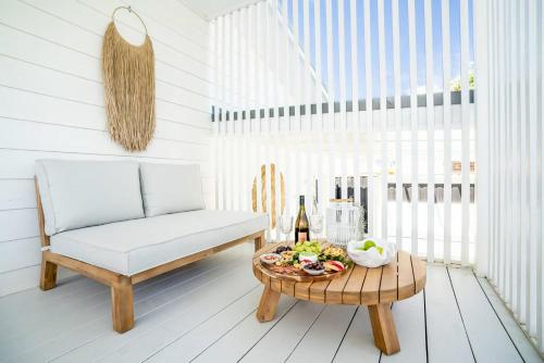a white room with a chair and a table with a bottle of wine at The White Haven of Gerringong in Gerringong