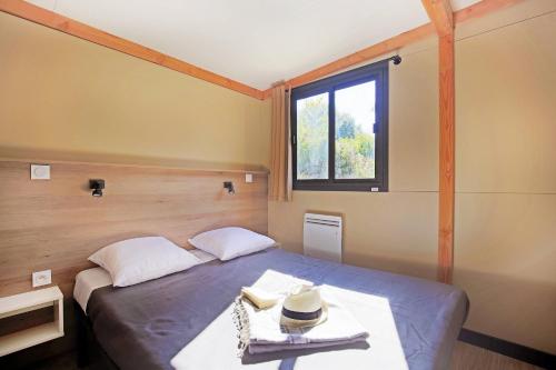 une chambre avec un lit et une fenêtre dans l'établissement Huttopia Beaulieu sur Dordogne, à Beaulieu-sur-Dordogne