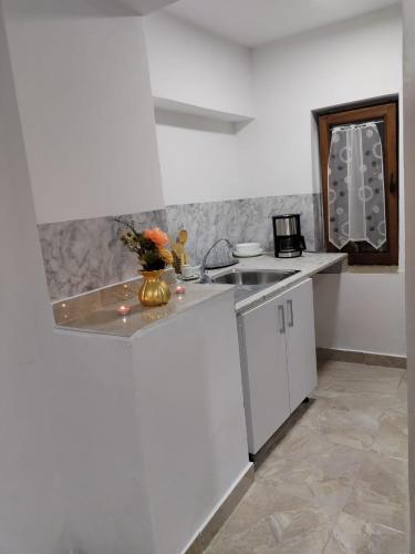 a white kitchen with a sink and a counter top at Casa Haidu in 2 Mai