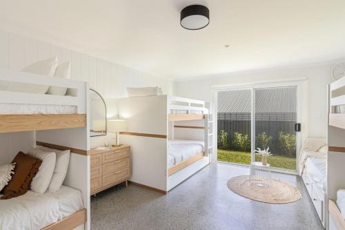 a bedroom with white bunk beds and a window at The White Haven of Gerringong in Gerringong