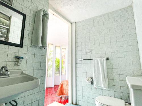 uma casa de banho com um WC branco e um lavatório. em Vista espectacular, privada y desayuno incluido! em Acapulco