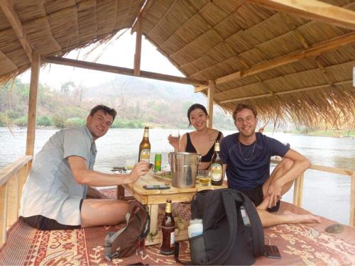 Namkhan View Luangprabang Resort في لوانغ برابانغ: مجموعة من ثلاثة أشخاص يجلسون على طاولة مع البيرة