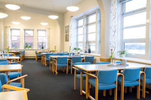 ein Esszimmer mit Tischen und blauen Stühlen in der Unterkunft Jugendherberge Lauenburg Zündholzfabrik in Hohnstorf