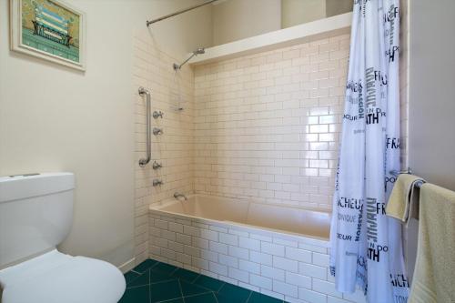 La salle de bains est pourvue d'une baignoire, de toilettes et d'une douche. dans l'établissement Foreshore Apartment 104, à Albany