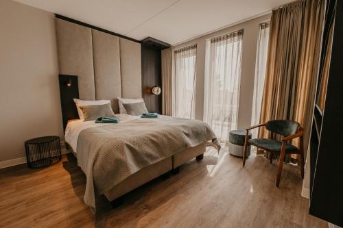 a bedroom with a large bed and a chair at Residence Oude Haven in Colijnsplaat