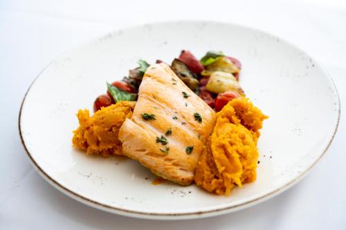 a white plate of food with fish and vegetables at Hotel Marina Port in Balatonkenese