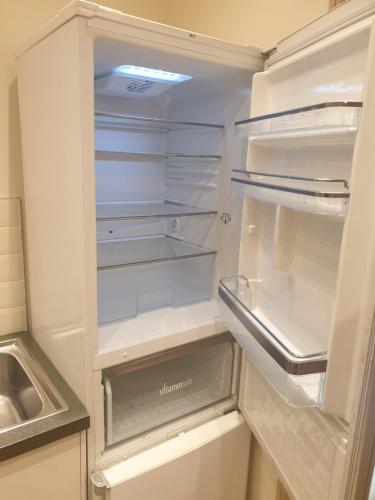 an empty refrigerator with its door open in a kitchen at London Luxury Apartments 3 Bedroom Sleeps 8 with 3 Bathrooms 4 mins walk to tube free parking in Ilford
