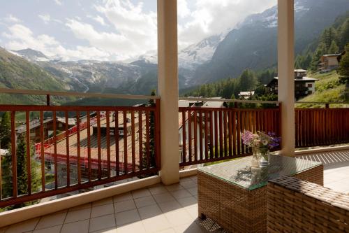a balcony with a table and a view of mountains at Victoria's Home - luxurious penthouse in Saas-Fee
