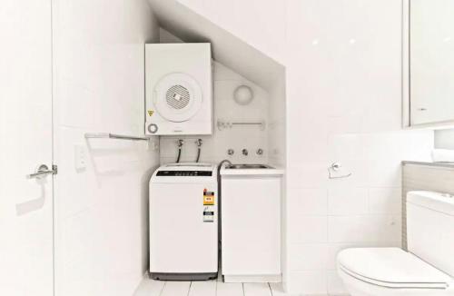 a white bathroom with a refrigerator and a toilet at Beautiful 2-Bed Apartment with ocean views of Barangaroo in Sydney