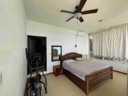 um quarto com uma cama, uma ventoinha de tecto e uma televisão em Villa Florita Beach House em El Remate
